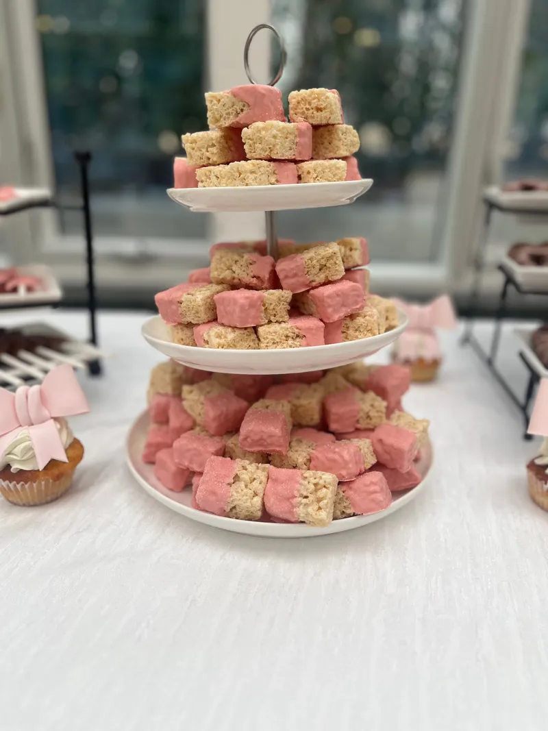 Three-tier display of pink-dipped rice krispie treats for a baby shower or pink-themed birthday celebration