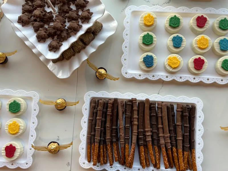 Harry Potter themed party with chocolate-covered Oreos featuring house crests, chocolate wands, and chocolate frogs by A Touch of Chocolate