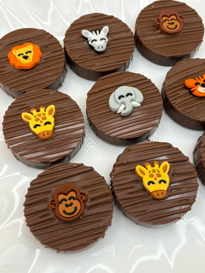 Safari themed chocolate-covered Oreos topped with lion, giraffe, monkey, elephant, zebra, and tiger fondant decorations by A Touch of Chocolate